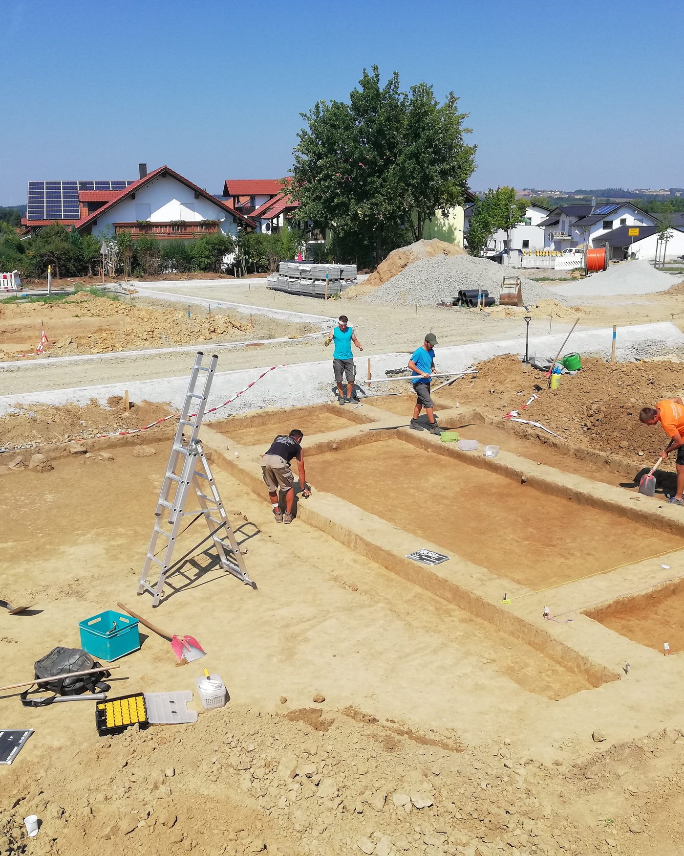Grabungsfläche mit freigelegten Befunden und Grabungsteam